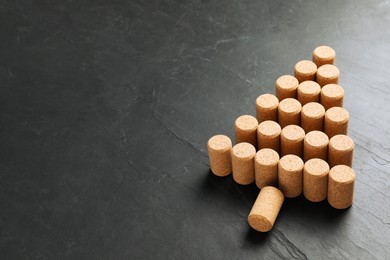Photo of Christmas tree made of wine corks on dark stone background. Space for text