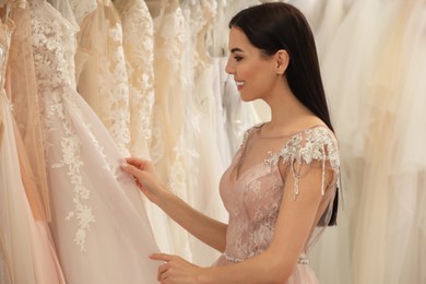 Young woman choosing wedding dress in salon