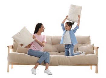 Photo of Young woman and her daughter having pillow fight on comfortable sofa against white background