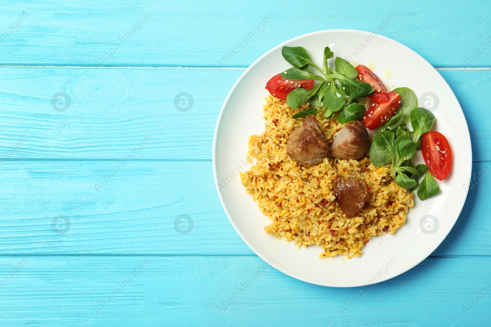 Photo of Plate of delicious rice pilaf and salad on wooden background, top view with space for text