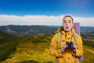 Image of Surprised tourist with backpack and binoculars in mountains