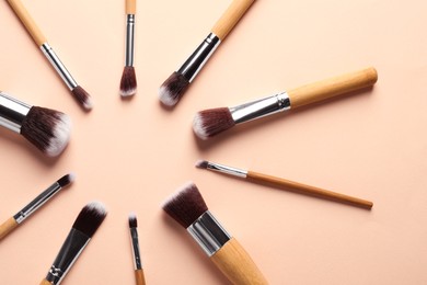Photo of Frame of makeup brushes on beige background, flat lay. Space for text