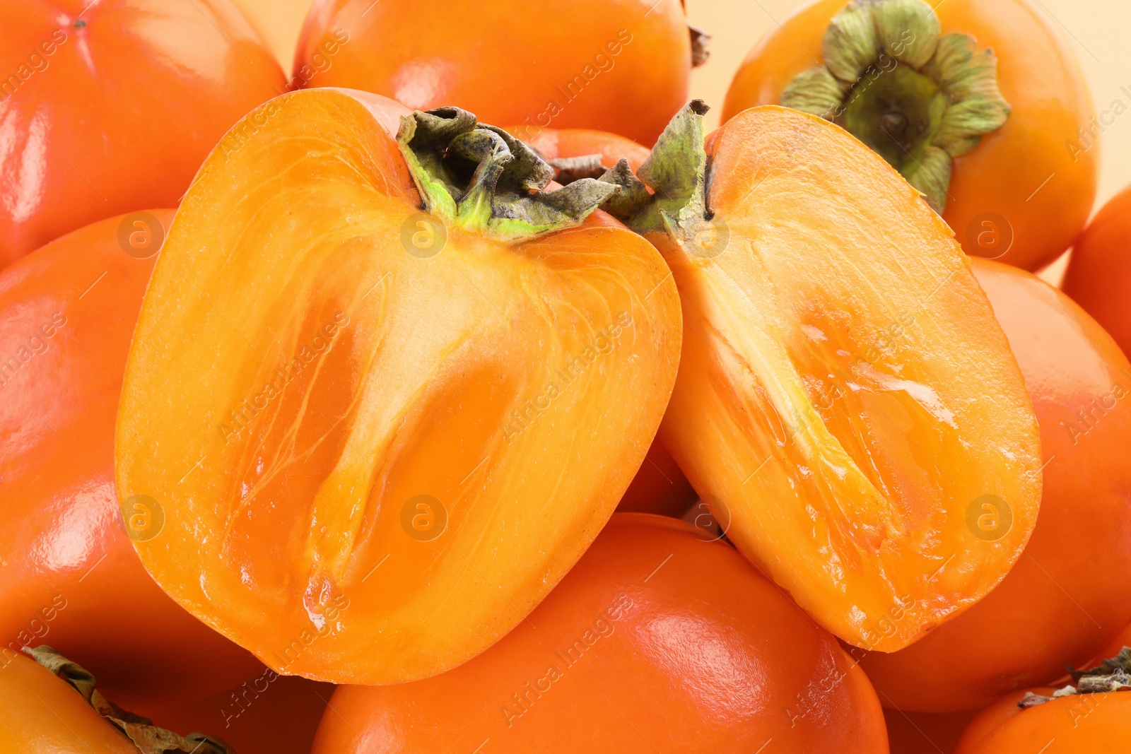 Photo of Whole and cut delicious ripe juicy persimmons as background, closeup