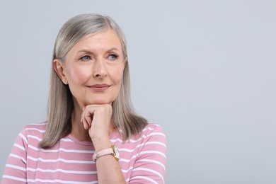 Portrait of beautiful senior woman on light grey background. Space for text