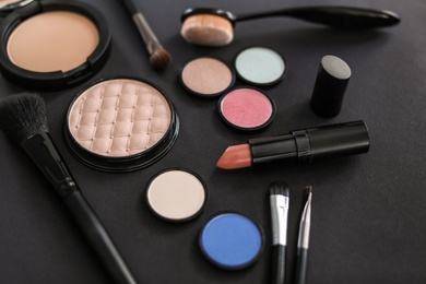 Different makeup brushes and cosmetic products on black background