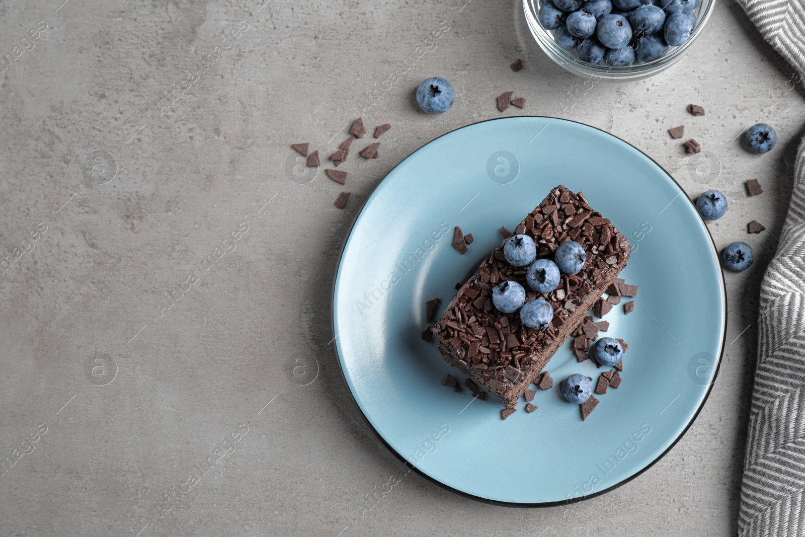 Photo of Delicious fresh chocolate cake served with blueberries on grey table, flat lay. Space for text