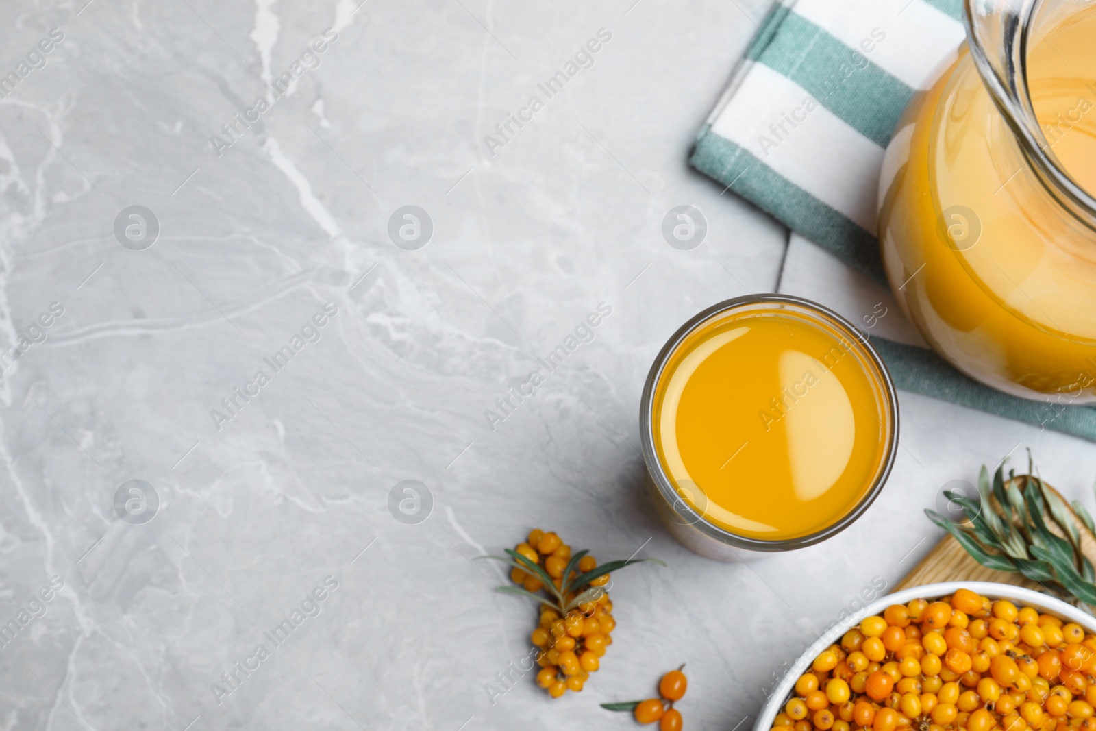 Photo of Sea buckthorn juice and fresh berries on light marble table, flat lay. Space for text