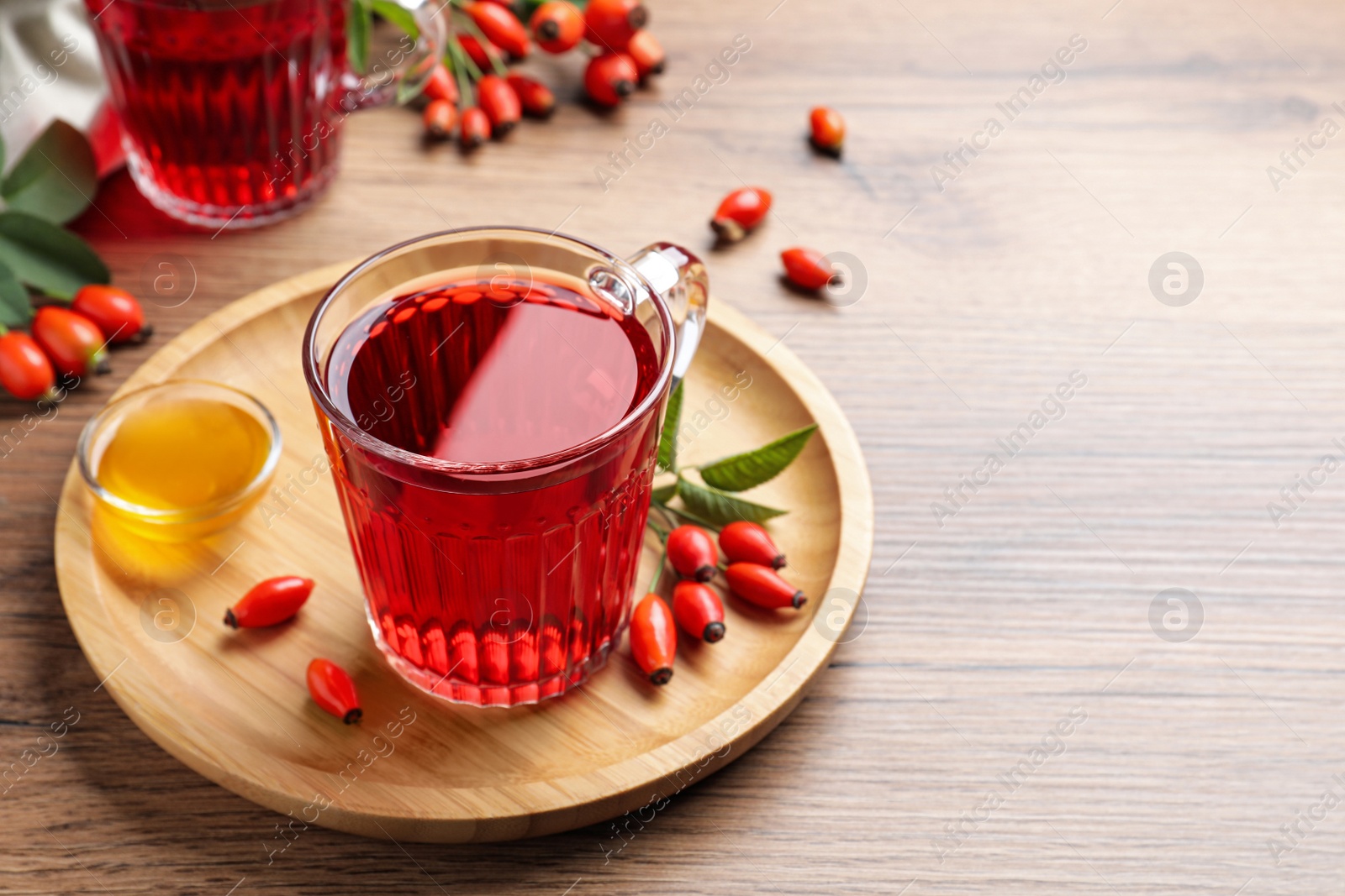 Photo of Fresh rose hip tea, honey and berries on wooden table. Space for text