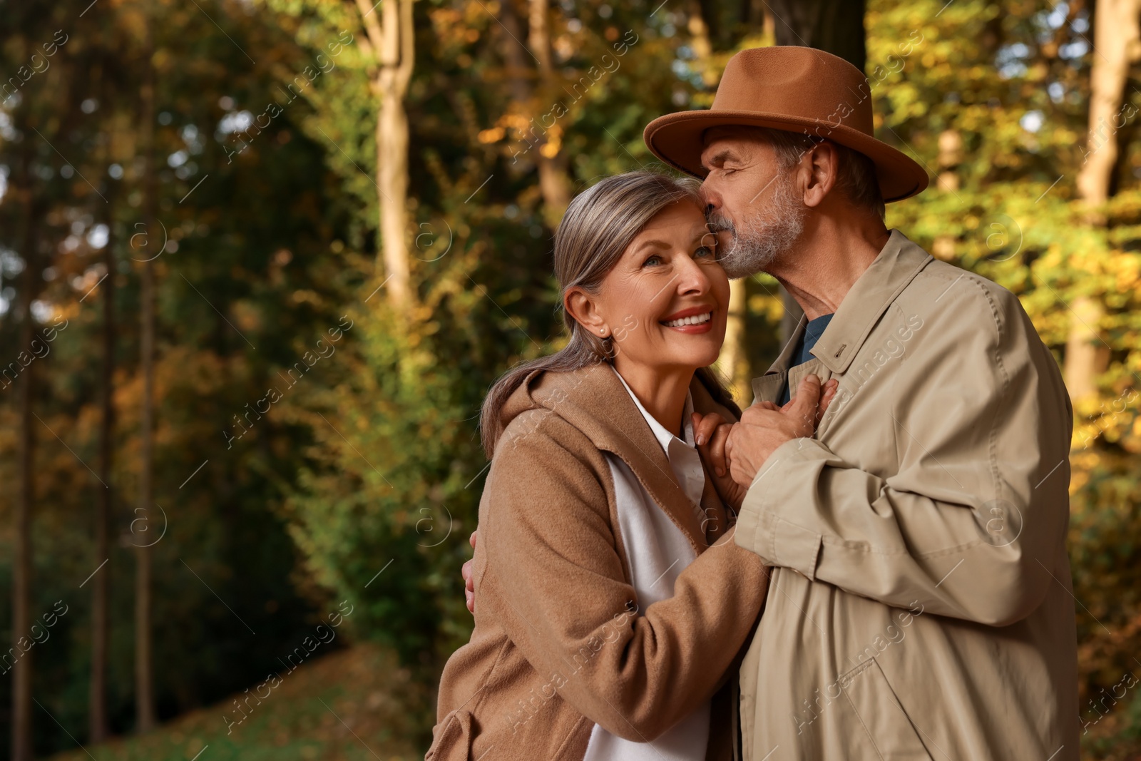 Photo of Affectionate senior couple in autumn park, space for text