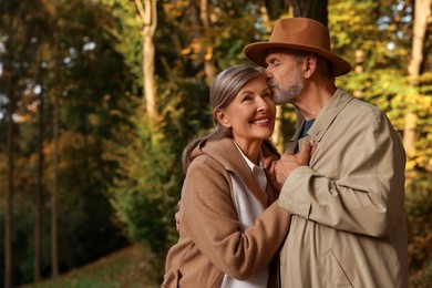 Photo of Affectionate senior couple in autumn park, space for text