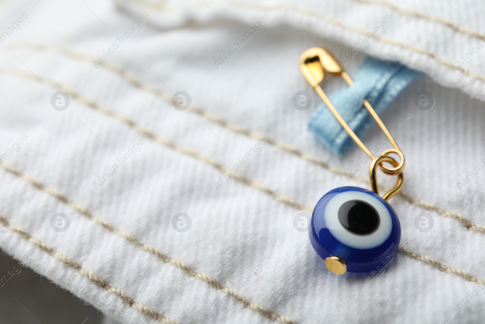 Photo of Evil eye safety pin on clothing, closeup