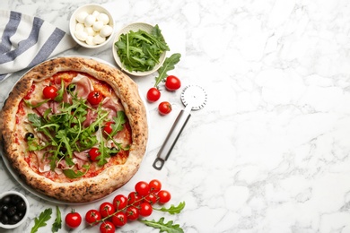 Photo of Tasty pizza with meat and arugula on white marble table, flat lay. Space for text