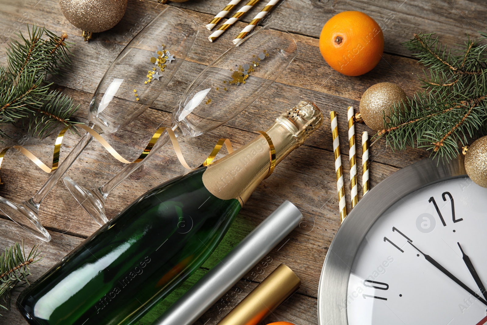 Photo of Christmas composition with bottle of champagne, glasses and clock on wooden background