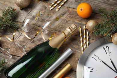 Photo of Christmas composition with bottle of champagne, glasses and clock on wooden background