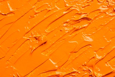 Photo of Beautiful strokes of orange oil paint as background, closeup