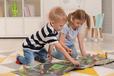 Little children playing with set of wooden road signs and toy cars indoors