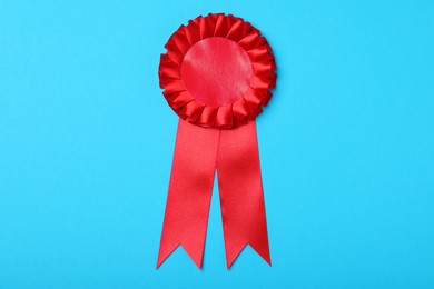 Photo of Red award ribbon on turquoise background, top view
