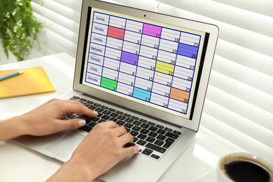 Photo of Young woman using calendar app on laptop in office, closeup