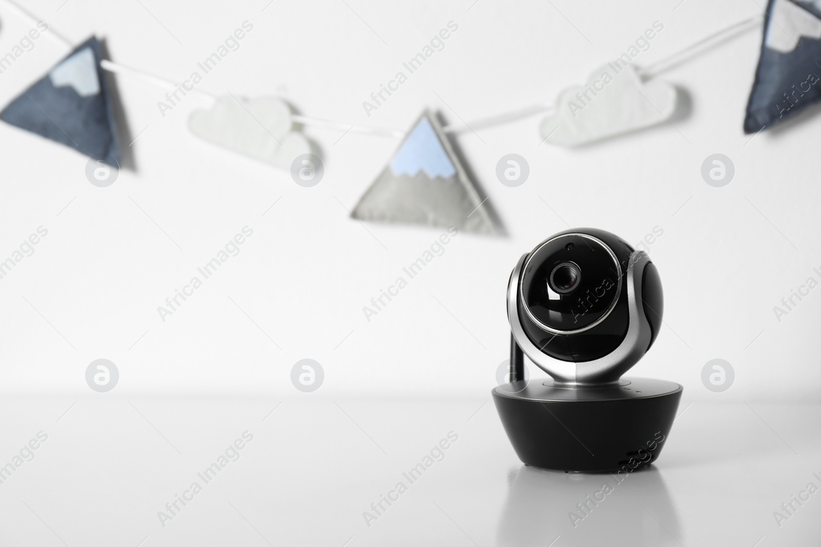 Photo of Modern CCTV security camera and nursery garland on background. Space for text