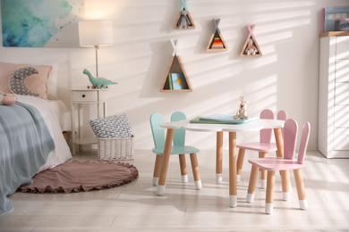 Small table and chairs with bunny ears in children's room interior