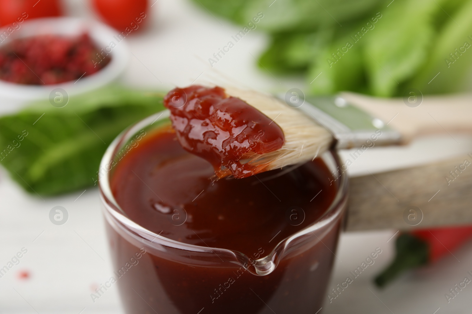 Photo of Marinade and basting brush on white table, closeup