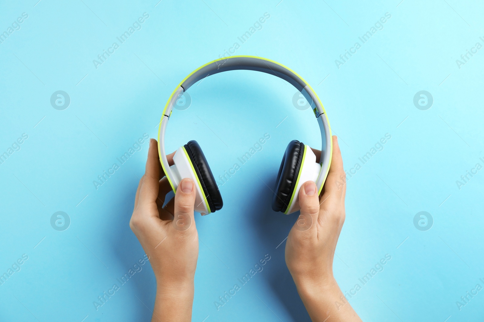 Photo of Woman holding headphones on color background, top view