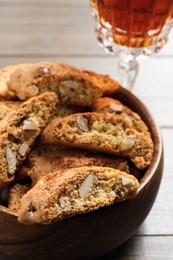 Photo of Traditional Italian almond biscuits (Cantucci) and glass of liqueur on wooden table, closeup