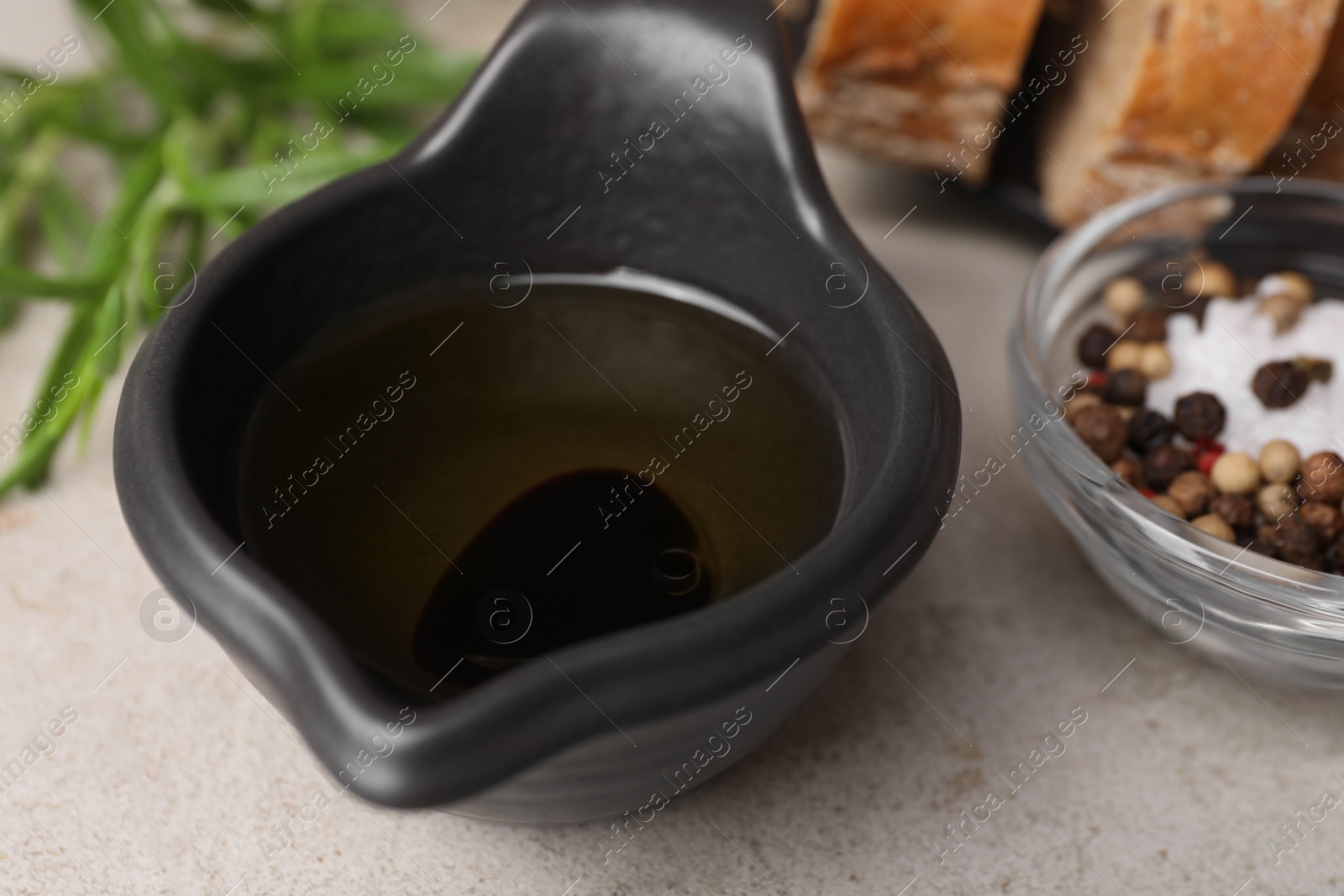Photo of Saucepan of organic balsamic vinegar with oil and spices on beige table, closeup