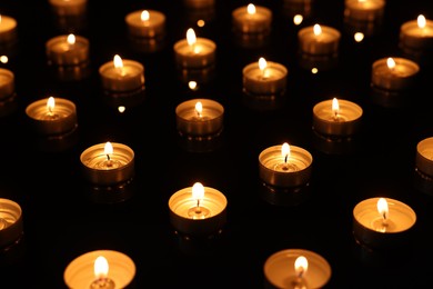 Burning candles on mirror surface in darkness