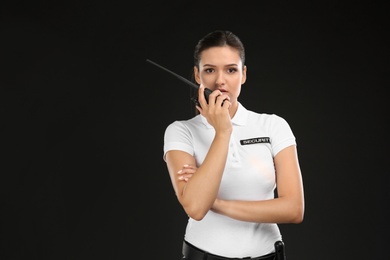 Photo of Female security guard using portable radio transmitter on dark background