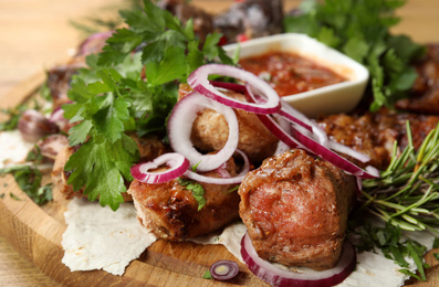 Photo of Delicious roasted meat with herbal on wooden board, closeup