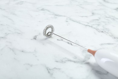 Photo of Milk frother wand on white marble table, closeup