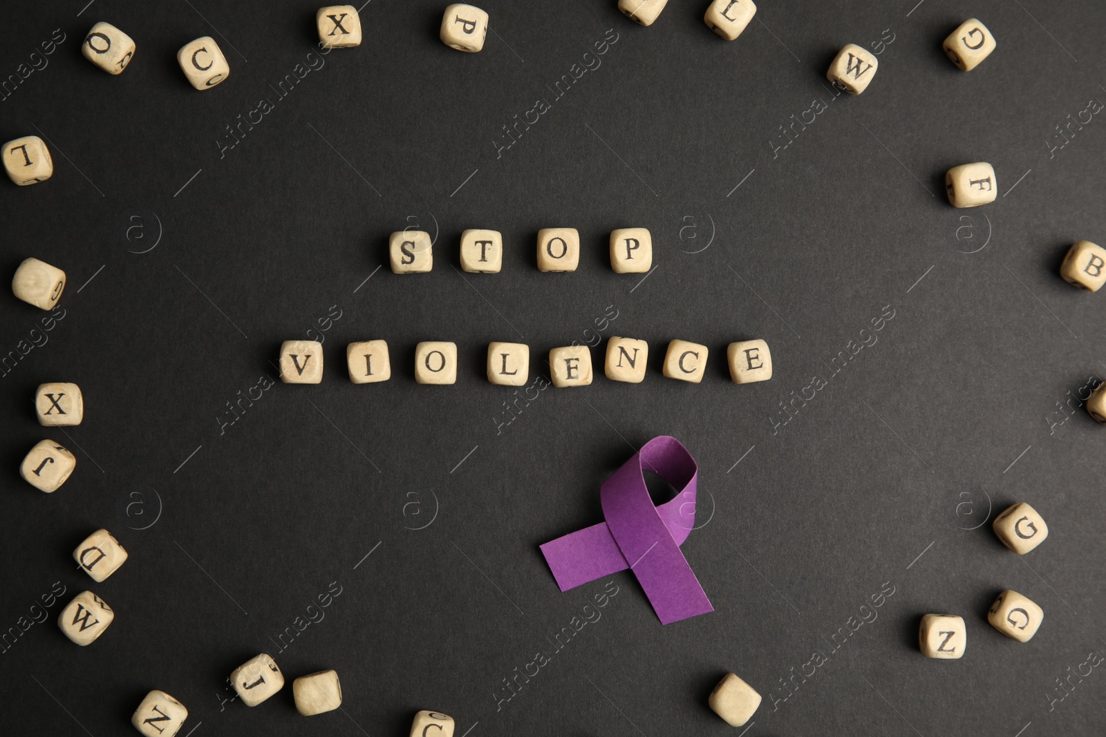 Photo of Purple ribbon and phrase STOP VIOLENCE made of wooden cubes on black background, flat lay