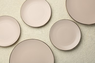 Beautiful ceramic plates on beige table, flat lay