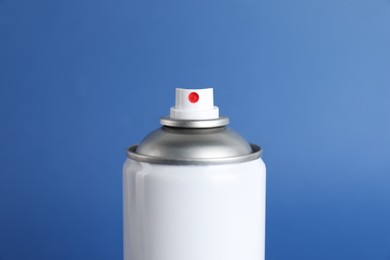Photo of Can of spray paint on blue background, closeup