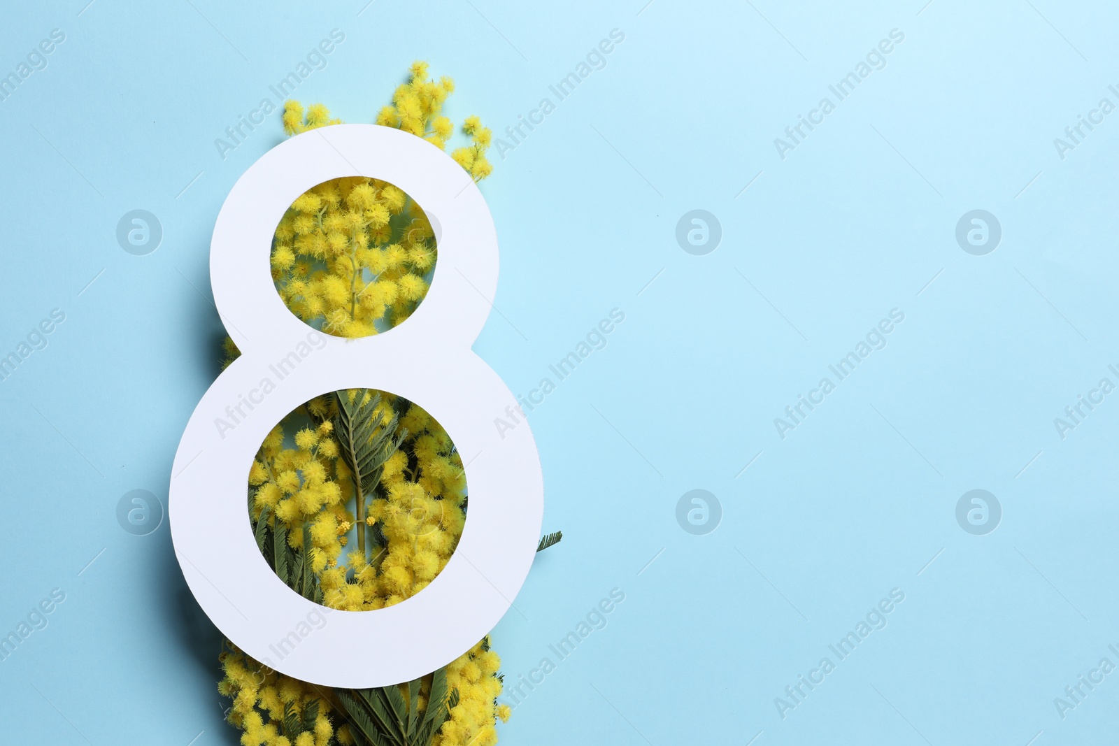 Photo of 8 March greeting card design with yellow mimosa flowers on light blue background, top view. Happy International Women's Day