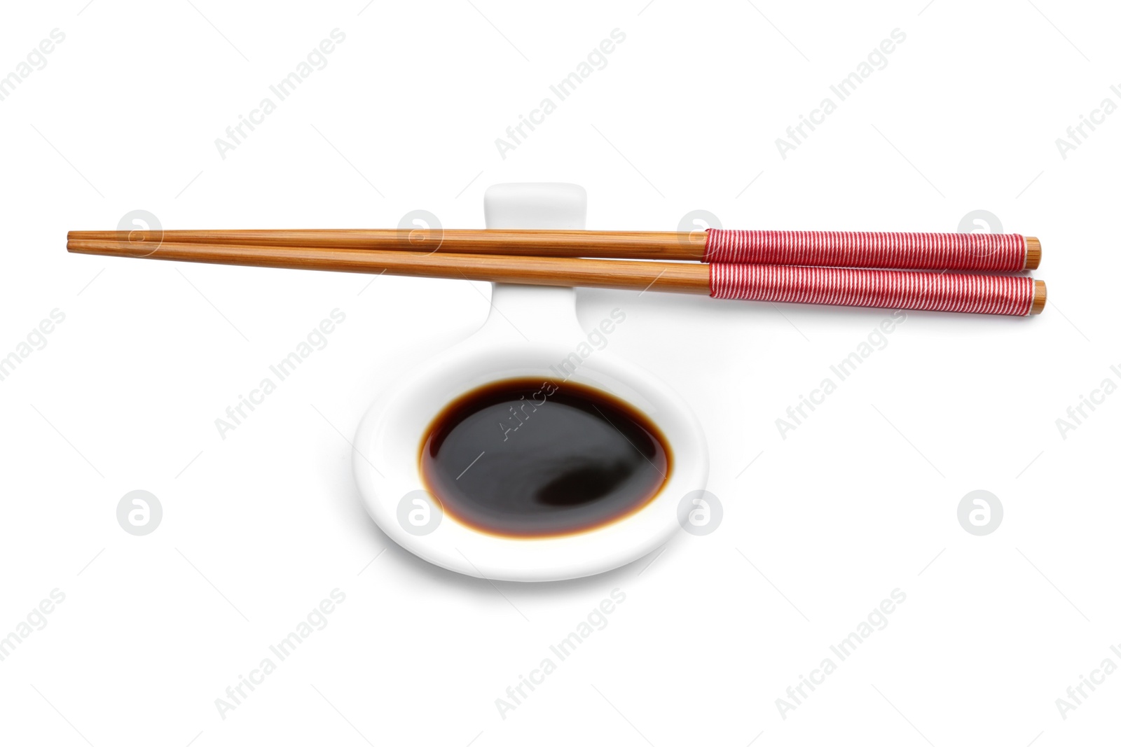 Photo of Dish of soy sauce with chopsticks on white background, top view