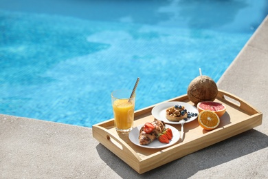 Tray with delicious breakfast near swimming pool. Space for text
