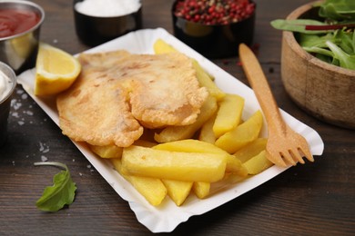 Photo of Delicious fish and chips served on wooden table, closeup