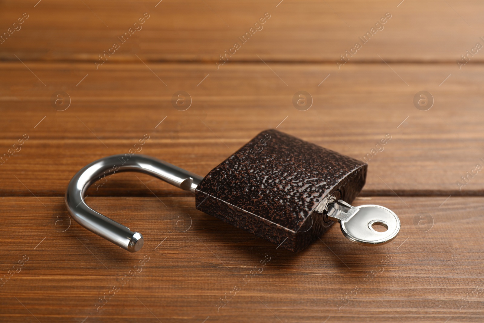 Photo of Modern padlock with key on wooden table