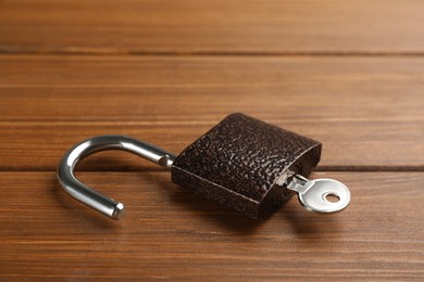 Photo of Modern padlock with key on wooden table