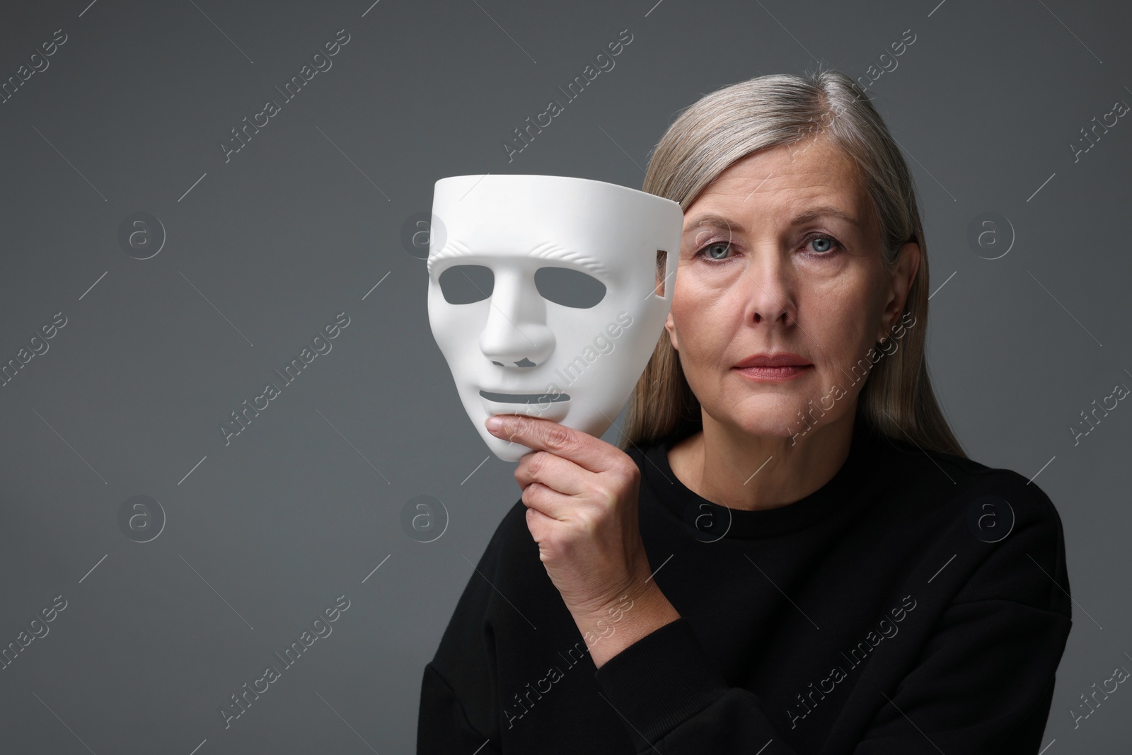 Photo of Multiple personality concept. Woman with mask on gray background, space for text