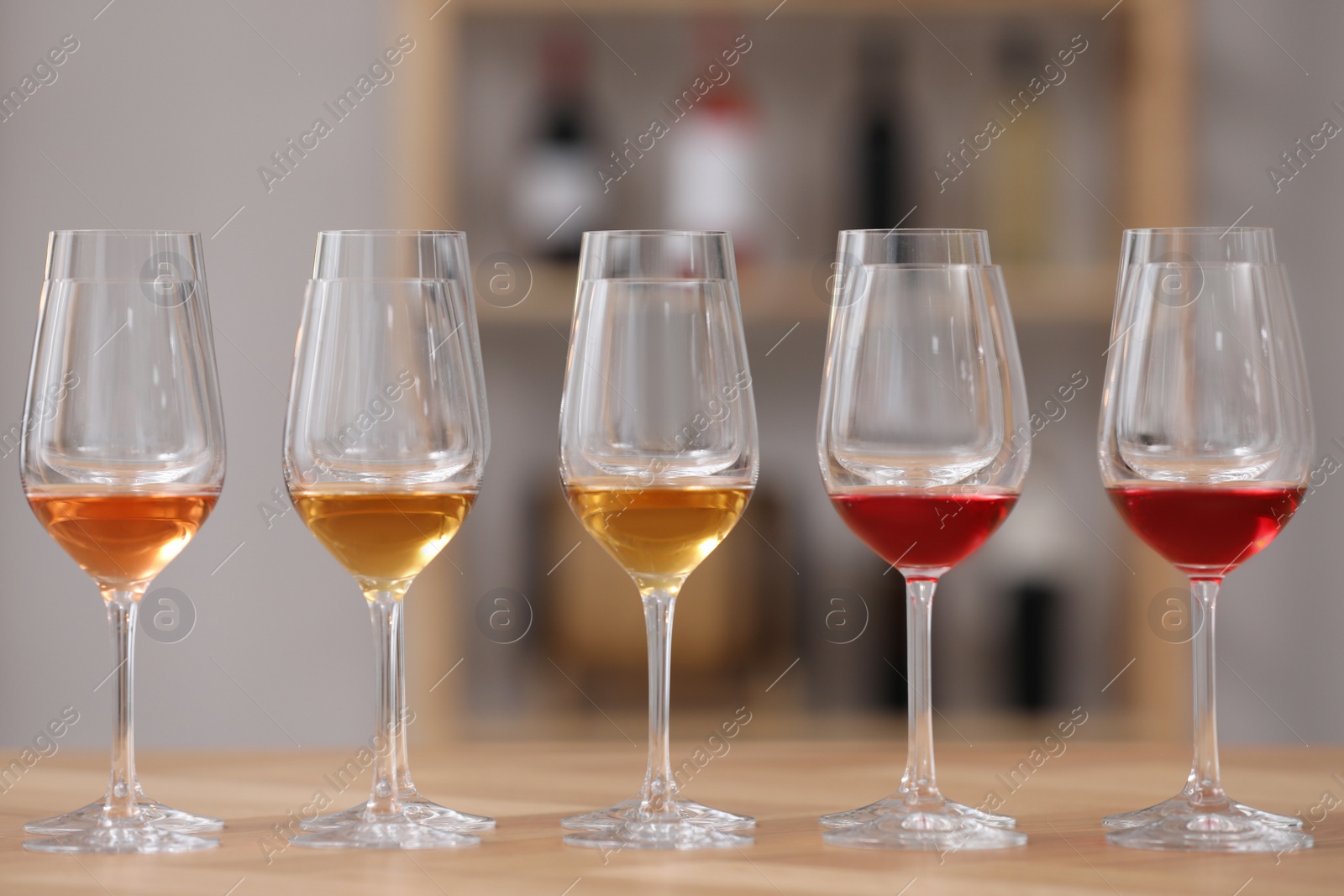 Photo of Different sorts of wine in glasses prepared for tasting on wooden table indoors