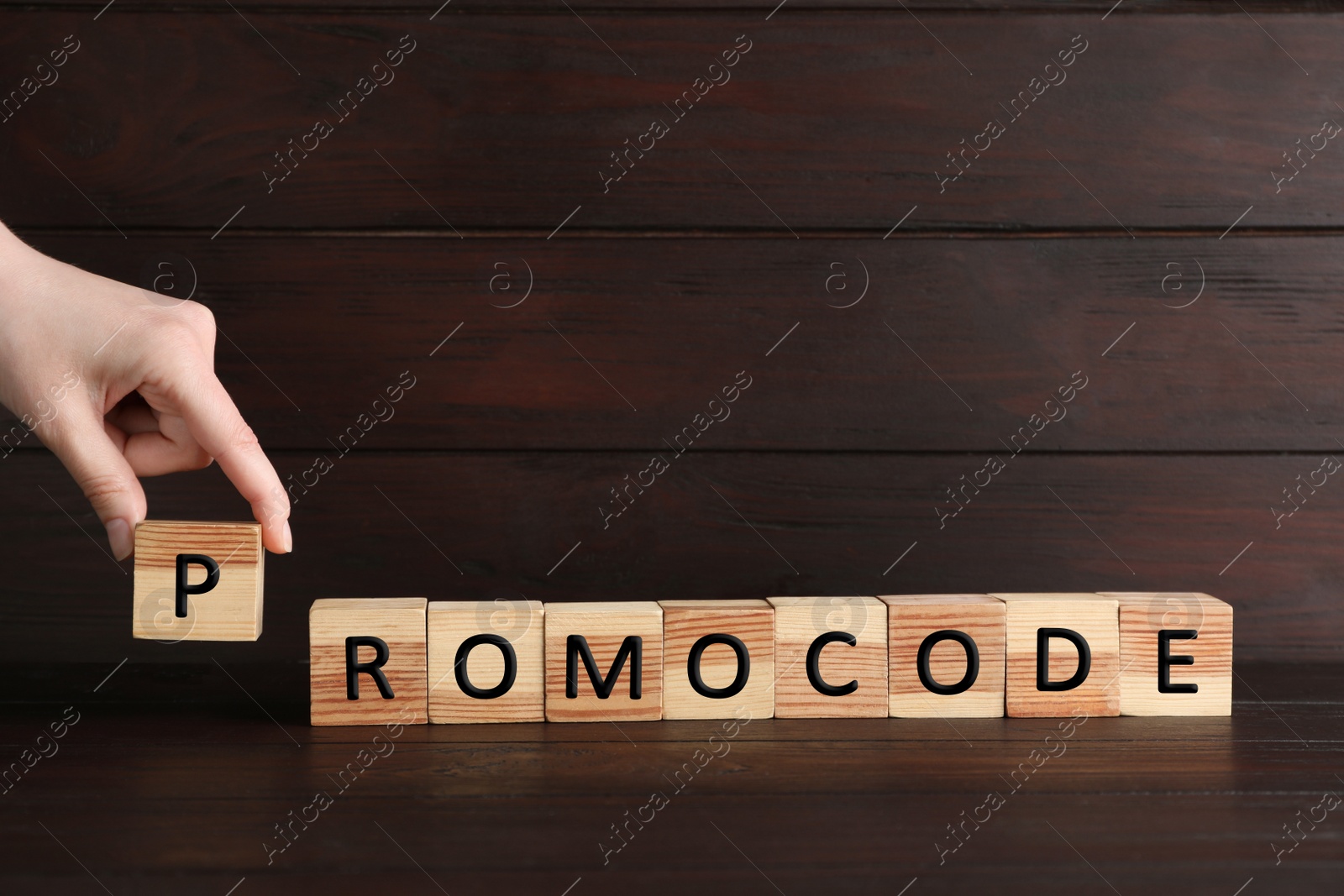 Photo of Woman making word Promocode with wooden cubes at table, closeup. Space for text