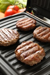 Photo of Delicious hamburger patties cooking on electric grill