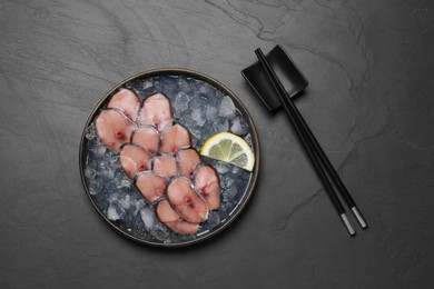 Raw mackerel slices, ice cubes, lemon and chopsticks on grey table, flat lay. Fish delicacy