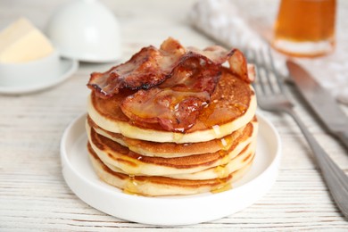 Photo of Delicious pancakes with maple syrup and fried bacon on white wooden table, closeup