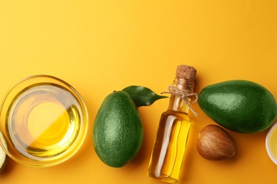 Photo of Cooking oil and fresh avocados on yellow background, flat lay. Space for text
