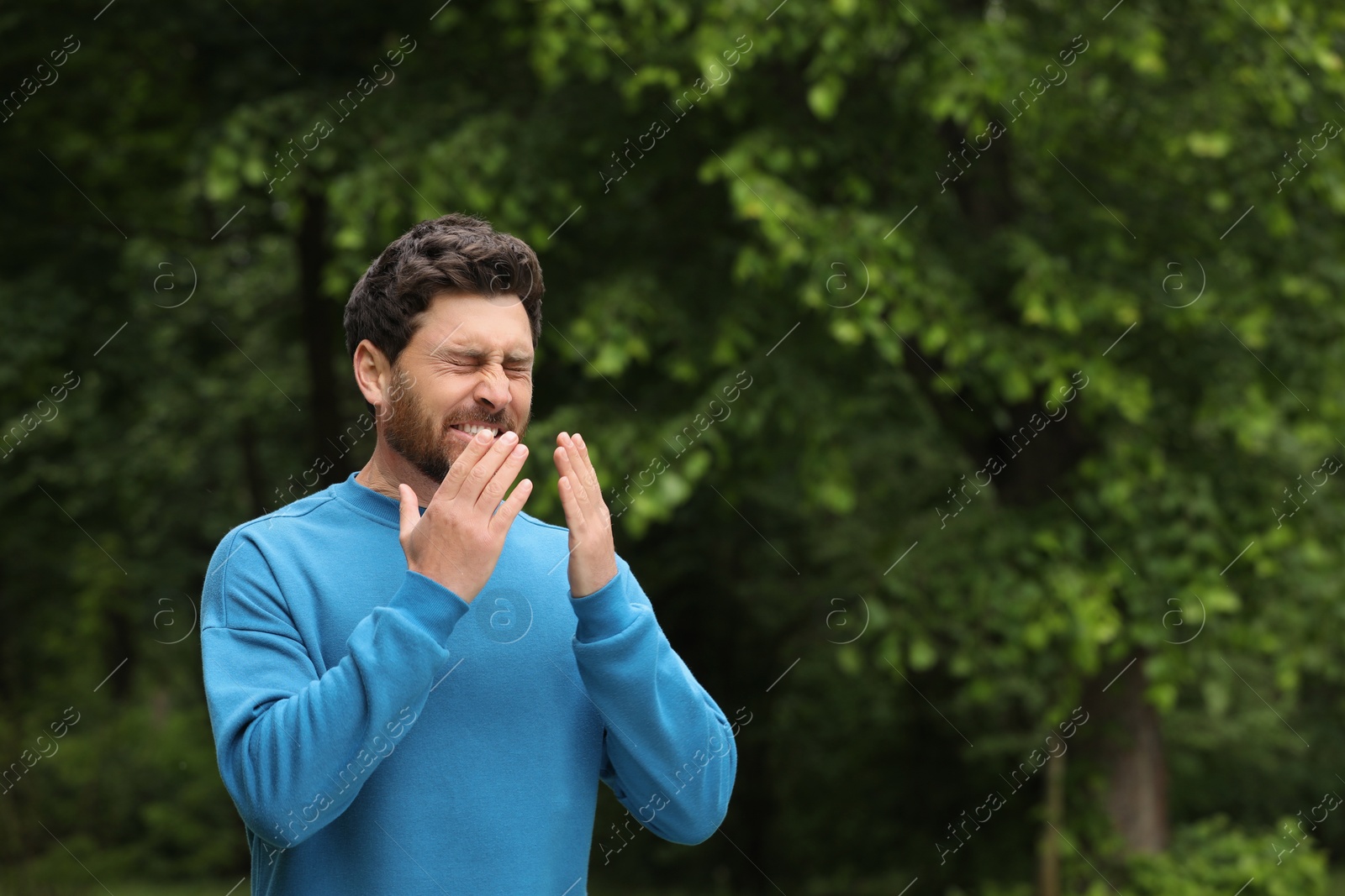 Photo of Man suffering from seasonal spring allergy outdoors, space for text