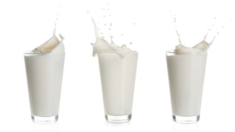 Image of Set with milk splashing out of glasses on white background 